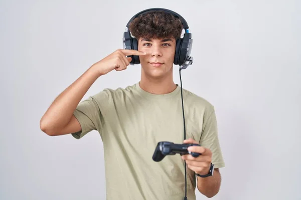 Adolescente Hispano Jugando Videojuegos Sosteniendo Controlador Apuntando Con Dedo Mano —  Fotos de Stock