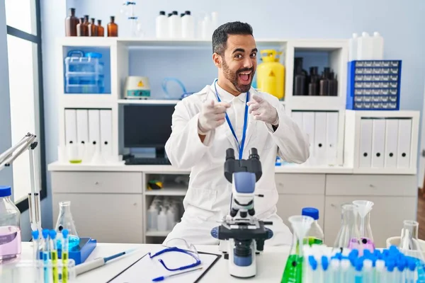 Laboratuvarda çalışan sakallı, neşeli ve komik yüzüyle kamerayı işaret eden genç bir İspanyol. iyi enerji ve titreşimler. 
