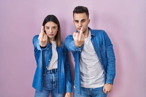 Young Hispanic Couple Standing Pink Background Showing Middle Finger Impolite — Stockfoto