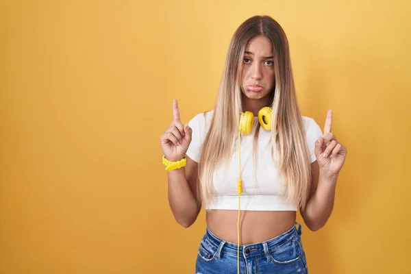 Young Blonde Woman Standing Yellow Background Wearing Headphones Pointing Looking — Stock Photo, Image