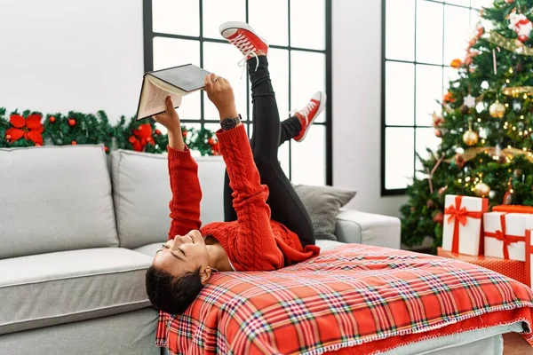 Young Hispanic Woman Reading Book Lying Christmas Tree Home — Fotografia de Stock