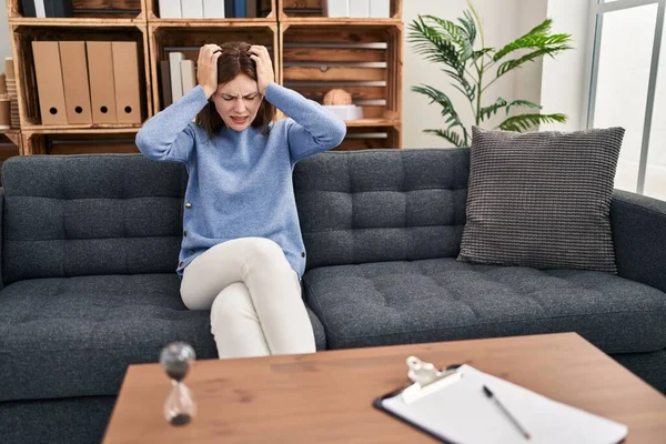 Muayenehanedeki genç esmer kadın acı ve migren yüzünden çaresiz ve stresli baş ağrısı çekiyor. Eller başının üstünde.. 