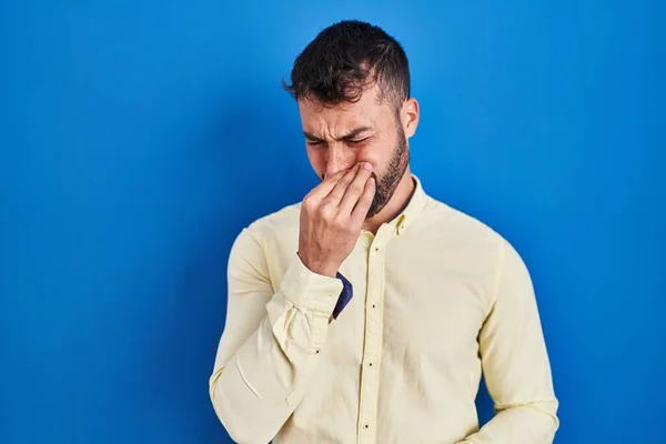 Handsome Hispanic Man Standing Blue Background Smelling Something Stinky Disgusting — Stockfoto