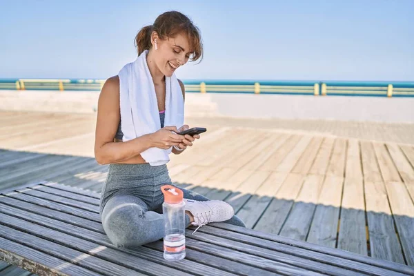 Beyaz Kadın Spor Giysisi Giyiyor Deniz Kenarında Akıllı Telefon Kullanıyor — Stok fotoğraf