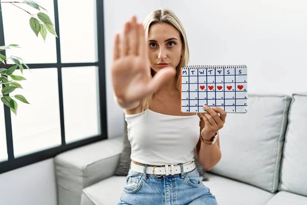 Young Blonde Woman Holding Heart Calendar Doing Stop Sing Palm — 图库照片