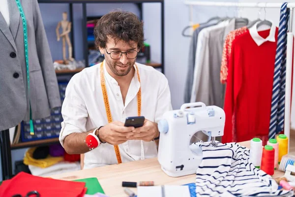 Jovem Hispânico Homem Alfaiate Sorrindo Confiante Usando Smartphone Fábrica Roupas — Fotografia de Stock