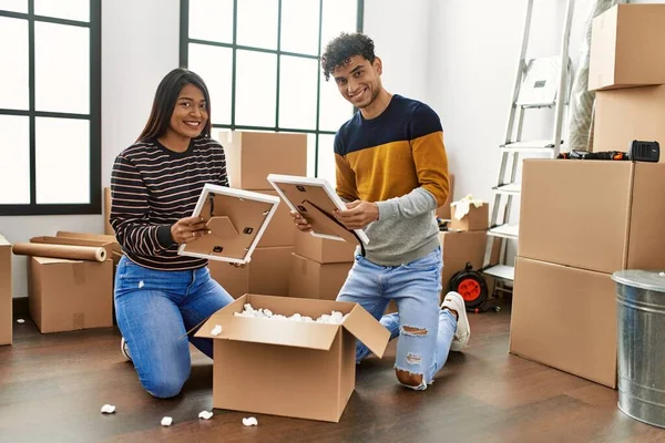 Young Latin Couple Smiling Happy Unboxing Cardboard Box New Home — ストック写真