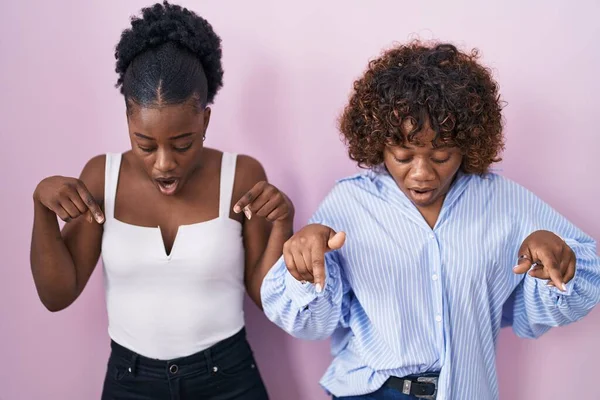 Two African Women Standing Pink Background Pointing Fingers Showing Advertisement — Fotografia de Stock