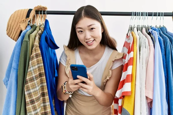 小売店でスマートフォンを使って服を探している若いアジアの女性 — ストック写真