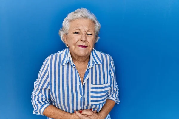 Yaşlı Bir Kadın Mavi Arka Planda Ayakta Duruyor Elleri Karnında — Stok fotoğraf