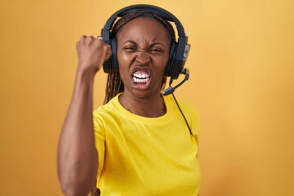 Mujer Afroamericana Escuchando Música Usando Auriculares Enojados Locos Levantando Puño —  Fotos de Stock