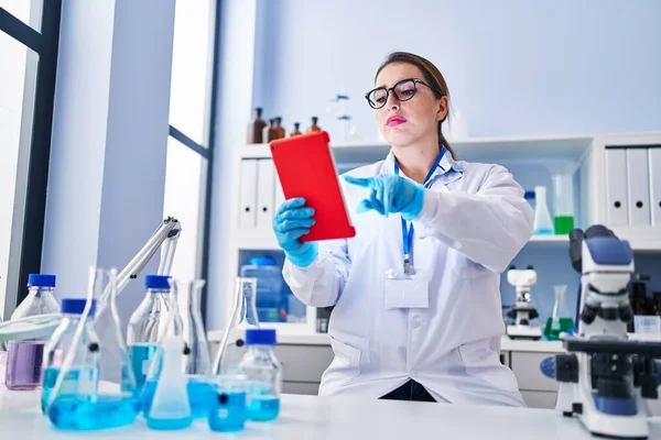 Young beautiful hispanic woman scientist using touchpad at laboratory