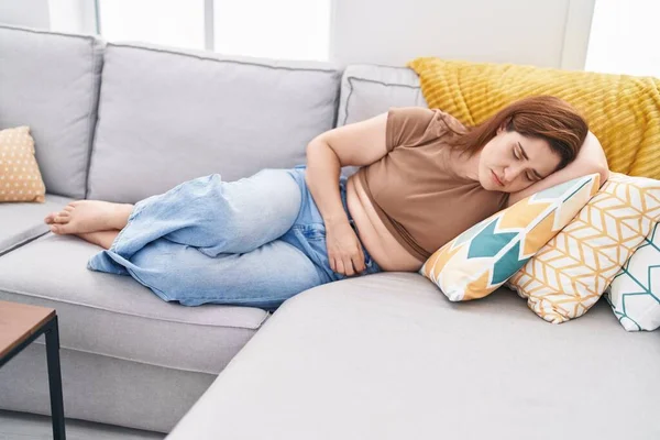Young Woman Suffering Menstrual Pain Lying Sofa Home — Stock fotografie
