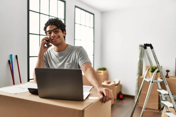 Jovem Hispânico Falando Smartphone Usando Laptop Nova Casa — Fotografia de Stock