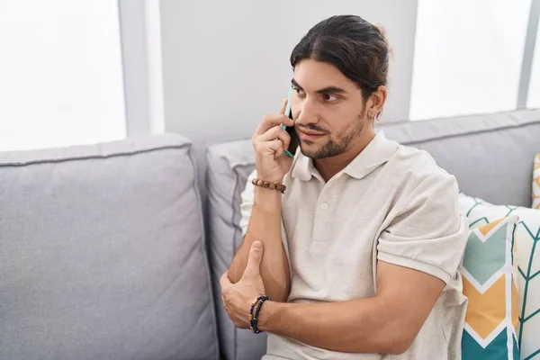 Young Hispanic Man Talking Smartphone Sitting Sofa Home — Stockfoto