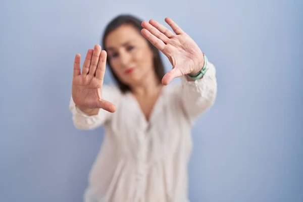 中年惊慌失措的女人站在蓝色的背景上 用手和手指头 镜头透视 — 图库照片