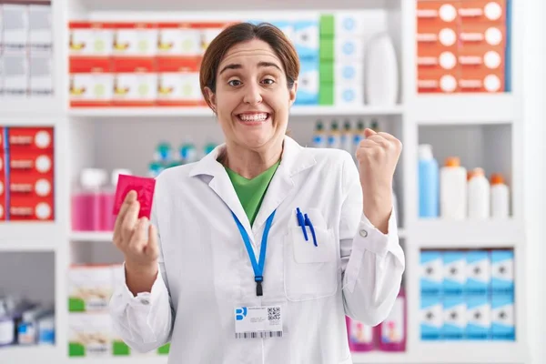 Mujer Morena Trabajando Farmacia Sosteniendo Condón Gritando Orgullosa Celebrando Victoria — Foto de Stock