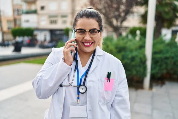 年轻美丽的女医生在公园用智能手机自信地微笑 — 图库照片