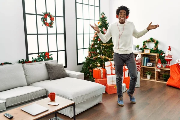 在家里听音乐在圣诞树旁跳舞的年轻的非洲裔美国人 — 图库照片