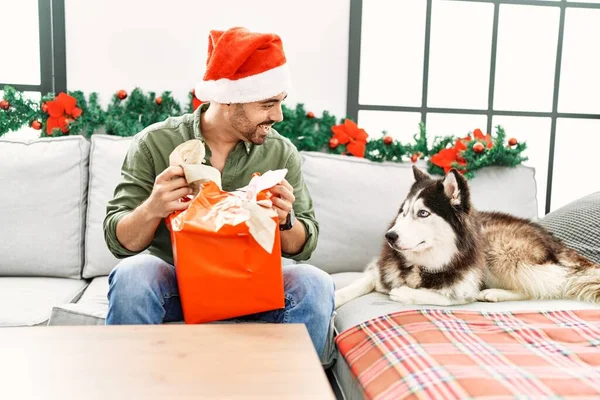 Jovem Hispânico Homem Unboxing Presente Sentado Sofá Com Cão Por — Fotografia de Stock