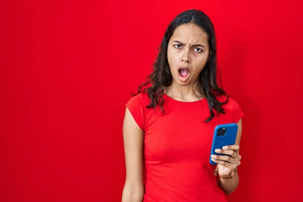 Junge Brasilianerin Mit Smartphone Über Rotem Hintergrund Schockgesicht Sieht Skeptisch — Stockfoto