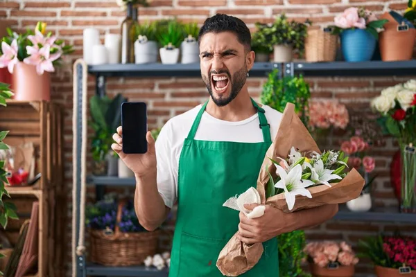 スマートフォンの画面を示す花屋で働いているヒスパニック系の若者は怒りと怒りで叫んで フラストレーションと激怒を叫んでいます 怒りと攻撃的な考え方 — ストック写真
