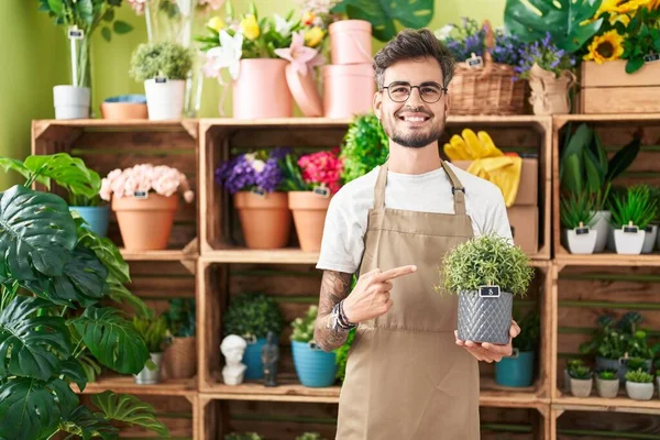 Mladý Hispánec Tetováním Pracuje Květinářství Drží Rostlina Úsměvem Šťastný Ukazující — Stock fotografie