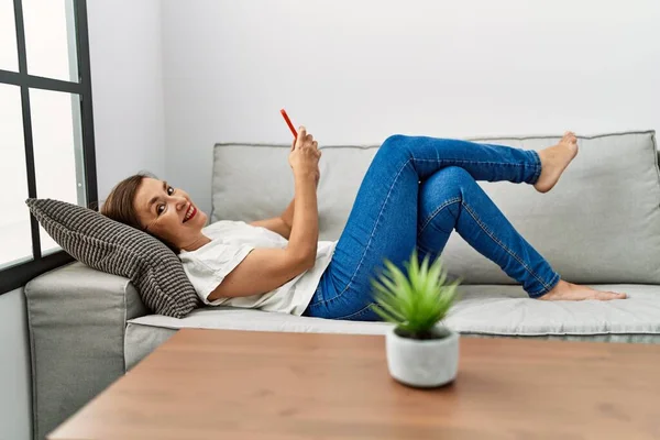 Middelbare Leeftijd Spaanse Vrouw Liggend Bank Met Behulp Van Smartphone — Stockfoto