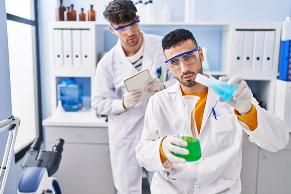 Laboratuvarda sıvıyı ölçen iki bilim adamı.