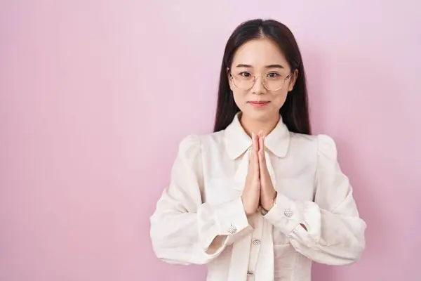 Ung Kinesisk Kvinna Står Över Rosa Bakgrund Med Händerna Tillsammans — Stockfoto