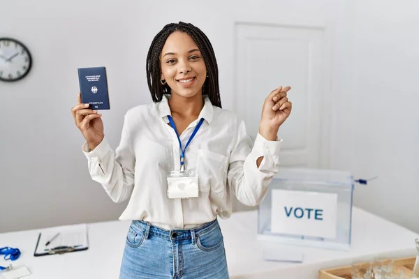 Young african american woman at political campaign election holding deutschland passport smiling happy pointing with hand and finger to the side