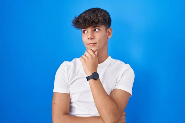 Adolescente Hispano Pie Sobre Fondo Azul Con Mano Barbilla Pensando — Foto de Stock