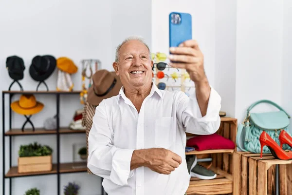 Senior man customer making selfie by the smartphone at clothing store