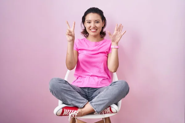 Hispanic Young Woman Sitting Chair Pink Background Showing Pointing Fingers — Stock Photo, Image