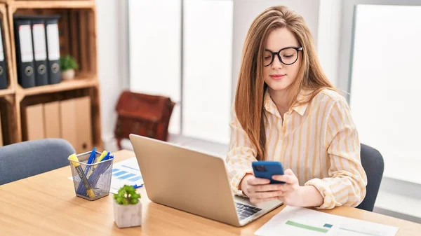 Genç Sarışın Kadını Ofiste Dizüstü Bilgisayar Akıllı Telefon Kullanıyor — Stok fotoğraf