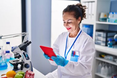 Laboratuvarda tabletle çalışan orta yaşlı İspanyol kadın.