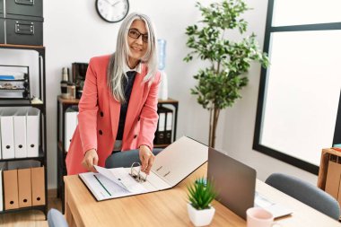 Ofiste çalışan, orta yaşlı, kır saçlı iş kadını.