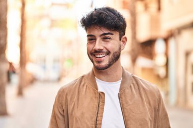 Young hispanic man smiling confident looking to the side at street