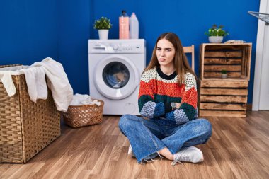Young hispanic girl doing laundry skeptic and nervous, disapproving expression on face with crossed arms. negative person. 