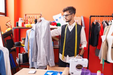Atölyede terzi tişörtü tutuyor.