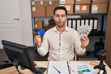 Sakallı genç İspanyol bir adam küçük işletme şirketinde çalışıyor. Elinde banknotlar ve kredi kartları var. Ağzı ve şaşı gözleri olan, deli ve komik bakışları olan bir adam.. 
