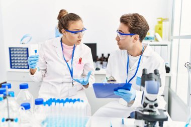 Man and woman wearing scientist uniform working at laboratory