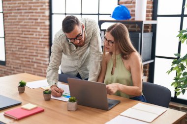 Man and woman business workers using laptop writing on document at office