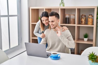 Man and woman couple hugging each other having video call at home