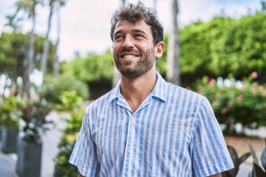 Genç İspanyol adam gülümseyerek şehirde mutlu mesut dikiliyor..