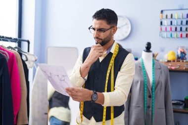 Genç Arap adam giyim fabrikasında elbise tasarımı yapıyor.