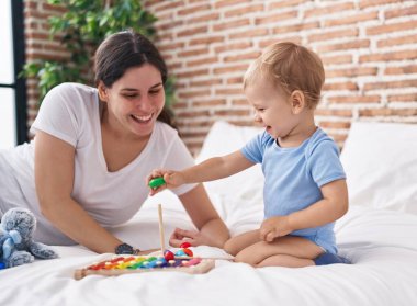 Anne ve oğlu yatakta uzanıp yatak odasında oynuyorlar.