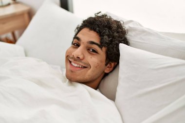 Genç İspanyol adam mutlu bir şekilde gülümsüyor. Yatak odasında yatıyordu..