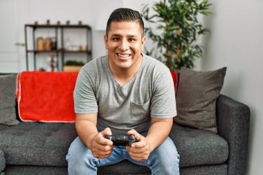Genç İspanyol gülümseyen adam evde video oyunu oynarken mutlu oluyor..