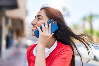 Young hispanic girl smiling confident talking on the smartphone at street